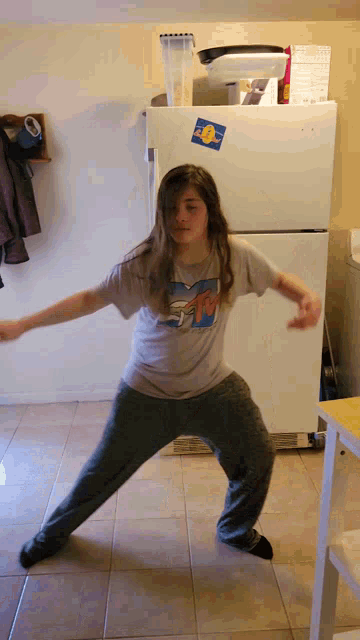 a girl wearing a mtv shirt is standing in front of a refrigerator