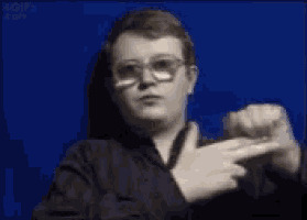 a young man wearing glasses is pointing his finger at something .