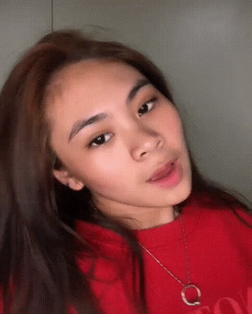 a woman wearing a red shirt and a necklace with a letter c on it