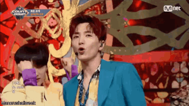 a man in a blue suit is singing into a microphone on a stage ..