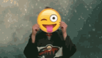 a person is holding a smiley face in front of their face with their tongue sticking out .