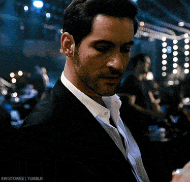 a man in a suit and white shirt is standing in a dark room ..