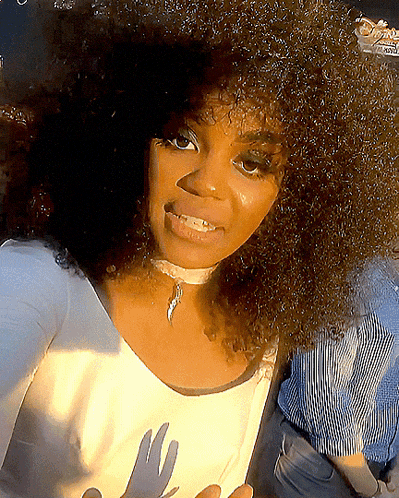 a woman with curly hair is wearing a choker and a white shirt