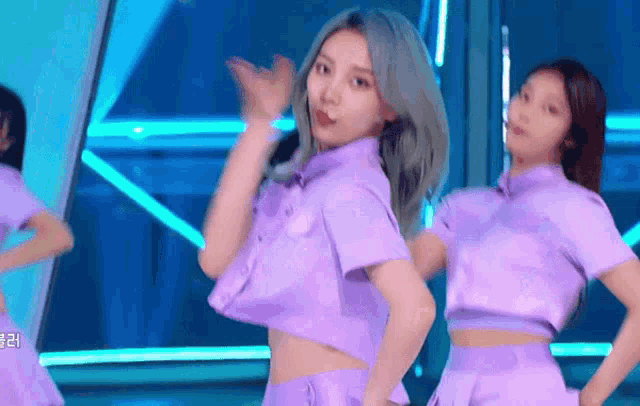 a woman in a purple shirt is dancing on a stage
