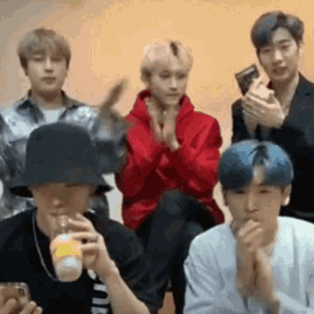 a group of young men are sitting in a room with their hands together .
