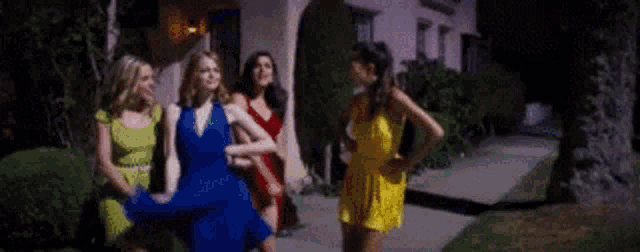 a group of women are standing on a sidewalk in front of a house .
