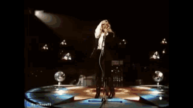 a woman is singing into a microphone on stage .
