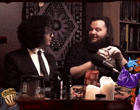 two men are sitting at a table with a candle and a microphone