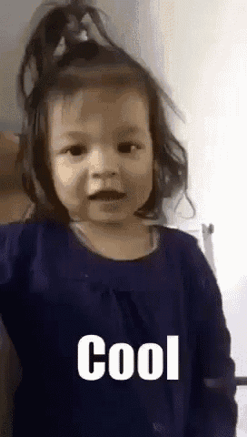 a little girl in a blue shirt is making a funny face and says cool .