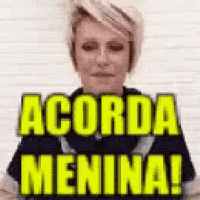 a woman is standing in front of a wall with the words acorda menina written on it .