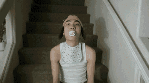 a young man wearing a pacifier and a bib is sitting on a set of stairs