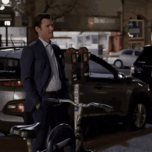 a man in a suit is standing next to a bike that has a sticker on it that says ' bicycle '