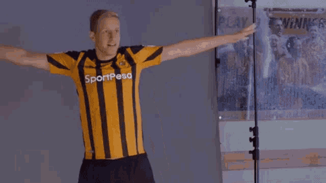 a man wearing a yellow and black striped shirt that says sportpesa