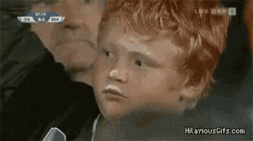 a boy with red hair is watching a soccer game on a tv screen