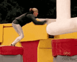 a gif of a woman jumping over a red and yellow object with abc written on it