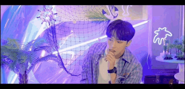 a young man is sitting in a room with a purple background and a fishing net .