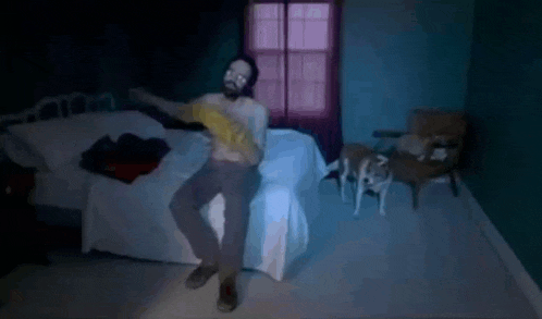 a man is sitting on a bed holding a baby in a dark room .