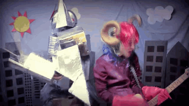 a person in a red wig is playing a guitar next to a person in a silver costume