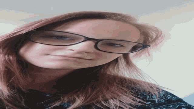 a woman wearing glasses looks at the camera