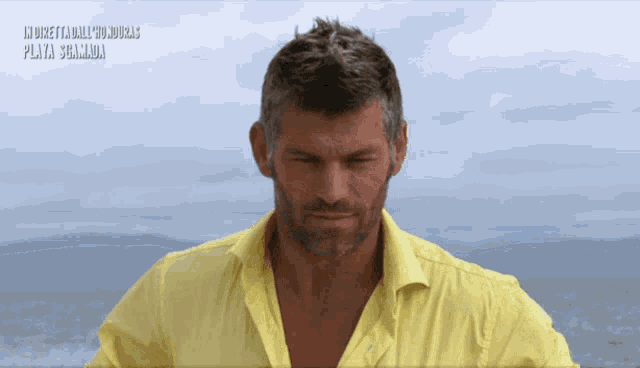a man in a yellow shirt stands in front of the ocean and the words playa salamanca