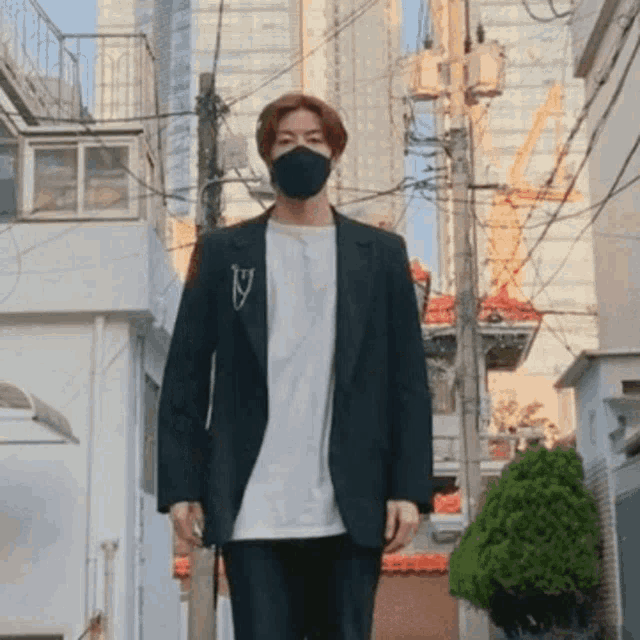 a man wearing a black face mask is walking down a city street