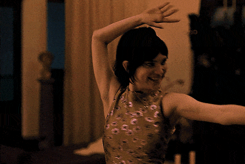 a woman in a gold dress is dancing in a room