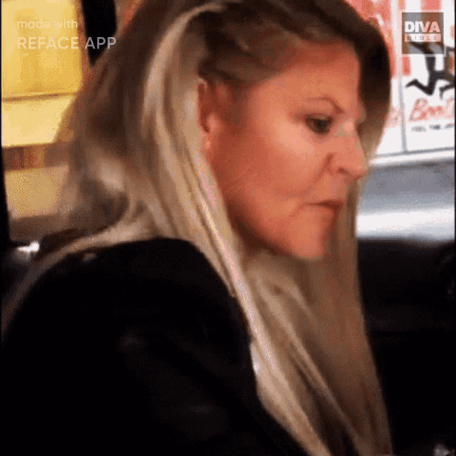 a woman with long blonde hair is sitting in a car with a diva logo on the side .