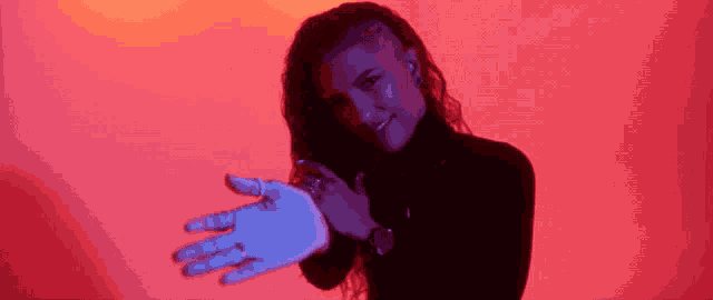 a woman in a black turtleneck is holding her hand out in front of her face