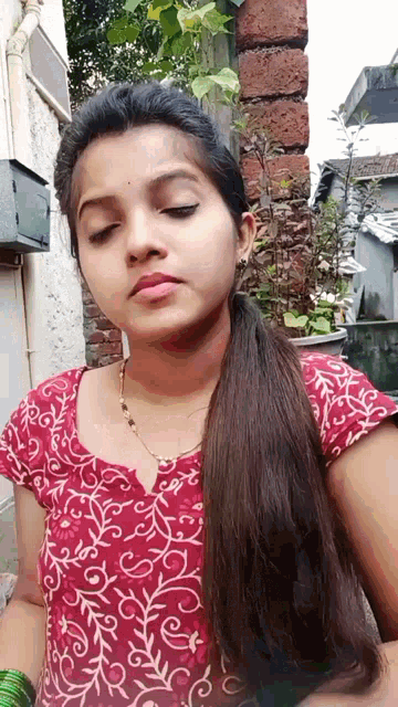 a woman with long hair is wearing a red top with white swirls on it