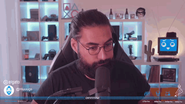 a man with glasses and a beard is talking into a microphone with the name hiuugg visible