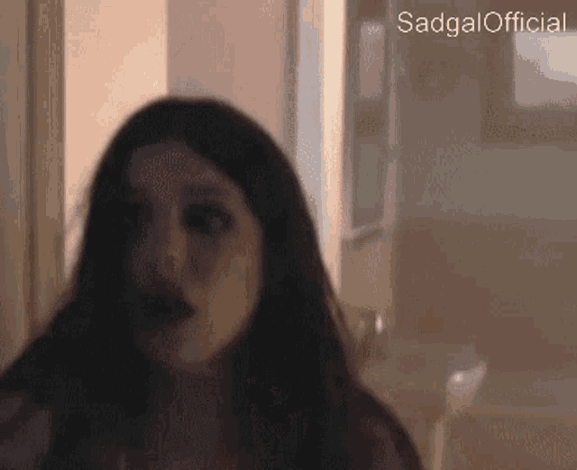 a woman in a dark room with the words sadgal official on the bottom