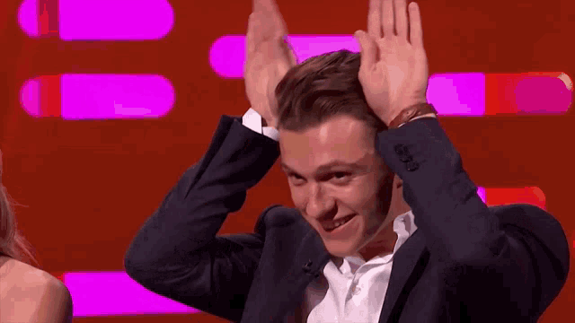 a man in a suit is holding his hands up in the air .