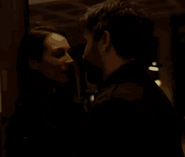 a man and a woman kissing in a dark room
