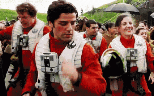 a group of people in red and white uniforms are walking in a line with umbrellas .