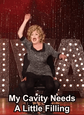a woman sitting in a chair with her hand in the air and the words " my cavity needs a little filling " below her