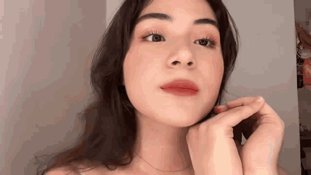 a close up of a woman 's face with her hands on her chin .