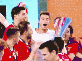 a group of soccer players are celebrating with a trophy in the background