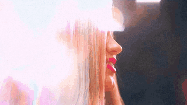 a close up of a woman 's face with long blonde hair and red lips