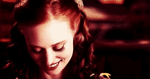 a close up of a woman 's face with red hair and a smile on her face .