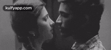 a man and a woman kissing in a black and white photo .