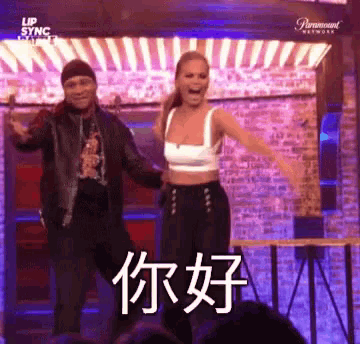 a man and a woman are dancing in front of a crowd and the woman is wearing a white top and black pants