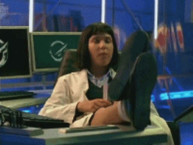 a woman in a lab coat sitting at a desk with her feet up