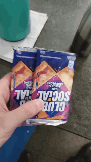 a person is holding a pack of club social crackers