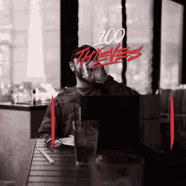 a black and white photo of a man sitting at a table with the words 100 thieves