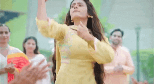 a woman in a yellow dress is dancing with a crowd of people .