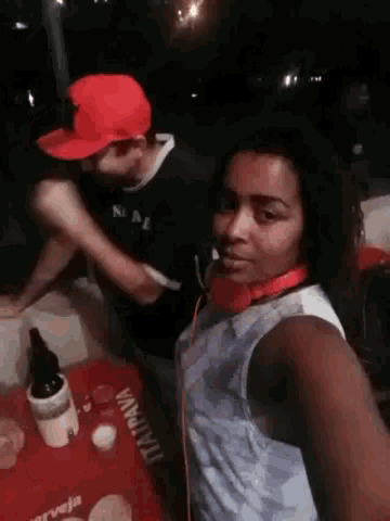 a man and a woman are standing next to each other at a table with a bottle of wine .