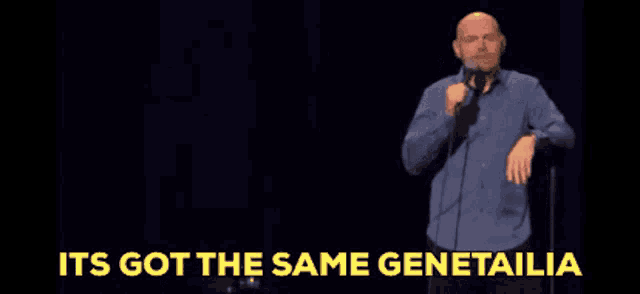 a bald man stands in front of a microphone with the words it 's got the same genetailia