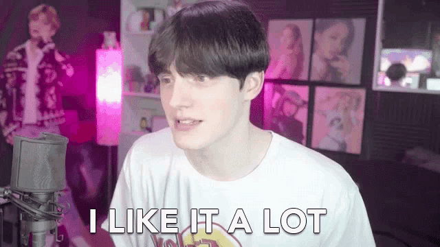 a young man is sitting in front of a microphone in a room and saying `` i like it a lot '' .