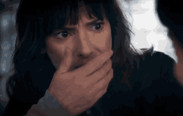 a woman is covering her mouth with her hand while looking at another woman .