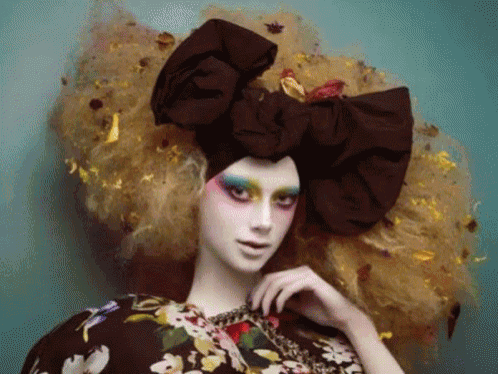 a woman with a large bow in her hair is wearing a floral top